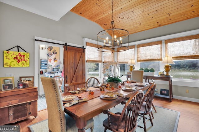 dining area featuring a barn door, a wealth of natural light, an inviting chandelier, and light wood-type flooring