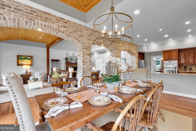 dining room featuring lofted ceiling, crown molding, a notable chandelier, and light wood-type flooring