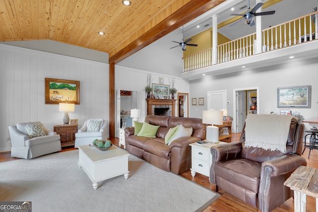 living room with beam ceiling, ceiling fan, high vaulted ceiling, light hardwood / wood-style floors, and a fireplace