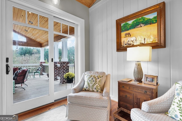 sitting room with wooden walls, wood ceiling, lofted ceiling, and wood-type flooring