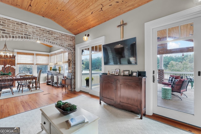 living room with lofted ceiling, wooden ceiling, light hardwood / wood-style floors, brick wall, and a chandelier