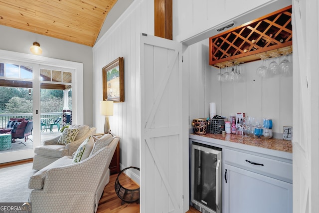 bar featuring lofted ceiling, wooden ceiling, wine cooler, light wood-type flooring, and white cabinetry