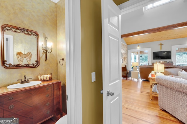 bathroom featuring hardwood / wood-style floors, vanity, beam ceiling, and crown molding