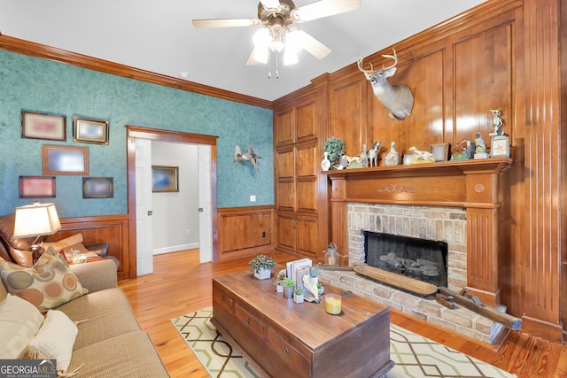 living room with crown molding, ceiling fan, light hardwood / wood-style floors, and a brick fireplace