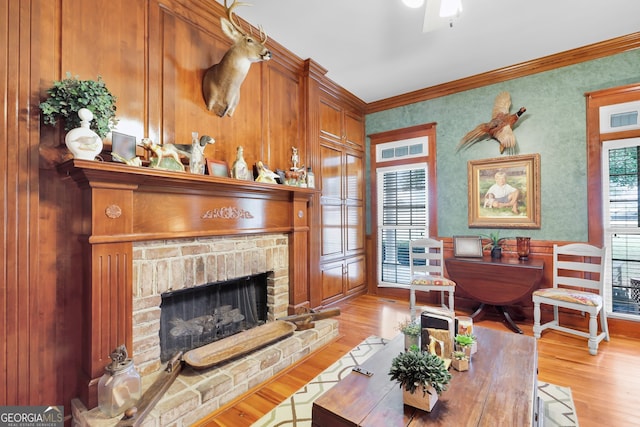 living room with a fireplace, light wood-type flooring, and crown molding