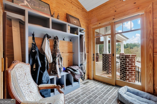 mudroom featuring vaulted ceiling, a healthy amount of sunlight, and wood walls