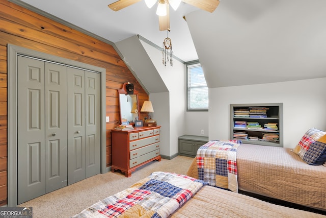 bedroom featuring ceiling fan, wood walls, light colored carpet, lofted ceiling, and a closet