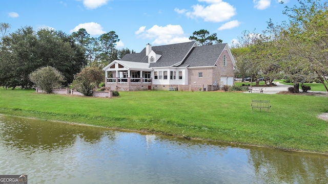 back of house with a sunroom, a water view, and a yard