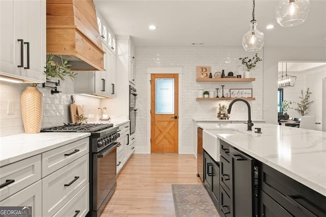 kitchen with white cabinetry, hanging light fixtures, premium range hood, and high end range