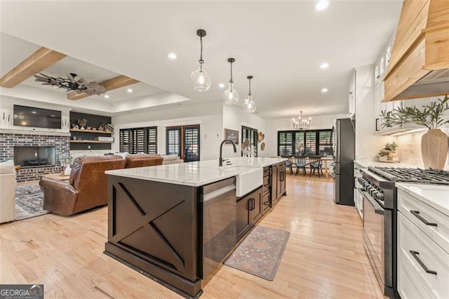 kitchen with white cabinets, a center island with sink, light hardwood / wood-style flooring, sink, and stainless steel appliances