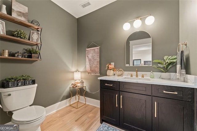 bathroom with vanity, vaulted ceiling, hardwood / wood-style flooring, and toilet