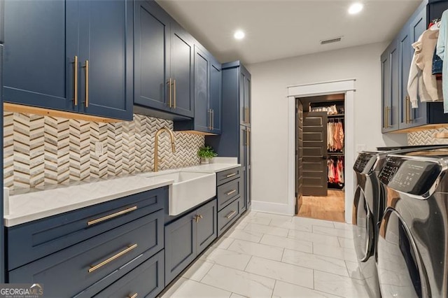 laundry area featuring sink, washing machine and clothes dryer, and cabinets