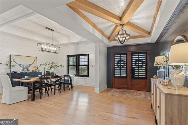 foyer entrance with french doors, beamed ceiling, light hardwood / wood-style flooring, and an inviting chandelier