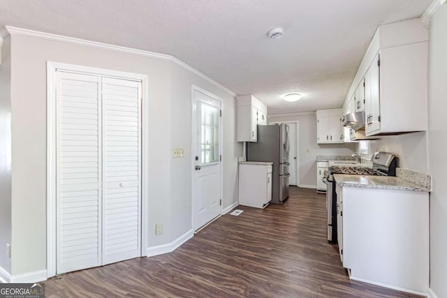 kitchen featuring dark wood-type flooring, stainless steel appliances, ornamental molding, white cabinets, and a textured ceiling