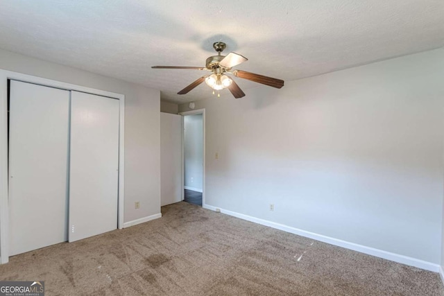 unfurnished bedroom with a closet, ceiling fan, carpet flooring, and a textured ceiling