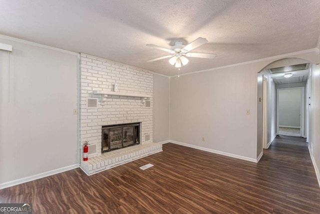 unfurnished living room featuring crown molding, dark hardwood / wood-style floors, a textured ceiling, and a brick fireplace