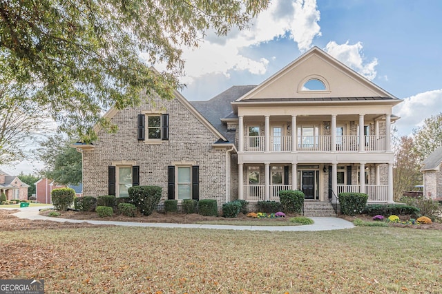 neoclassical home with a balcony, covered porch, and a front yard