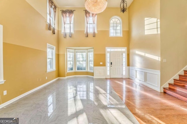 foyer featuring a towering ceiling, hardwood / wood-style flooring, a chandelier, and a wealth of natural light