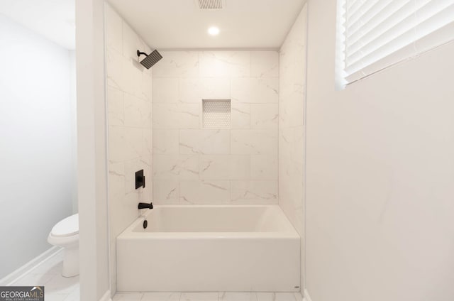 bathroom featuring toilet and tiled shower / bath