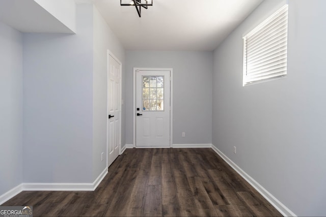 doorway to outside with a chandelier and dark hardwood / wood-style floors