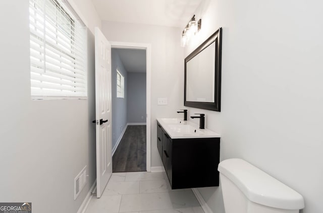 bathroom featuring toilet, vanity, and plenty of natural light