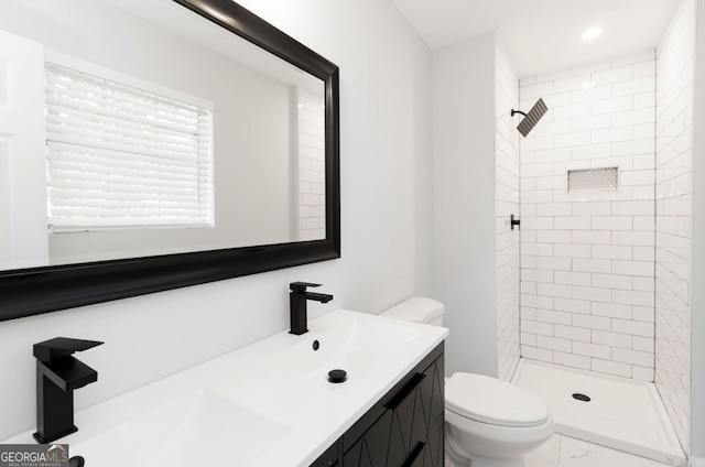 bathroom with vanity, toilet, and a tile shower