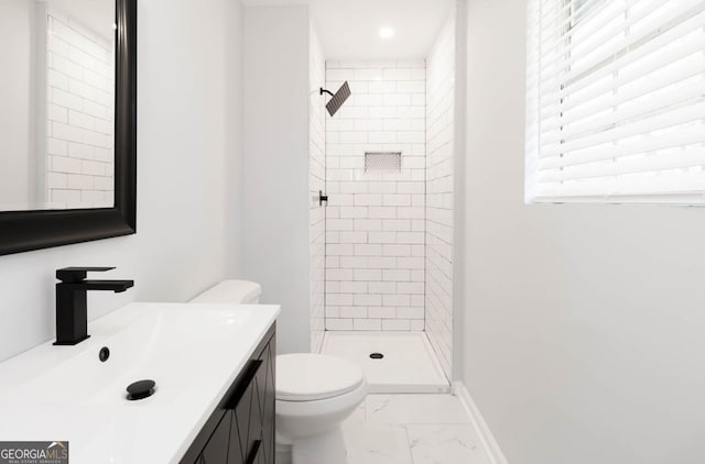 bathroom featuring toilet, vanity, plenty of natural light, and tiled shower