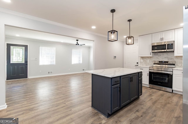 kitchen featuring a center island, hardwood / wood-style floors, white cabinetry, ceiling fan, and stainless steel appliances