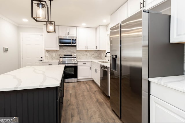 kitchen with light stone counters, dark hardwood / wood-style flooring, white cabinetry, pendant lighting, and stainless steel appliances