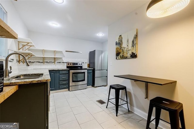 kitchen featuring decorative backsplash, stainless steel appliances, sink, light stone countertops, and light tile patterned flooring