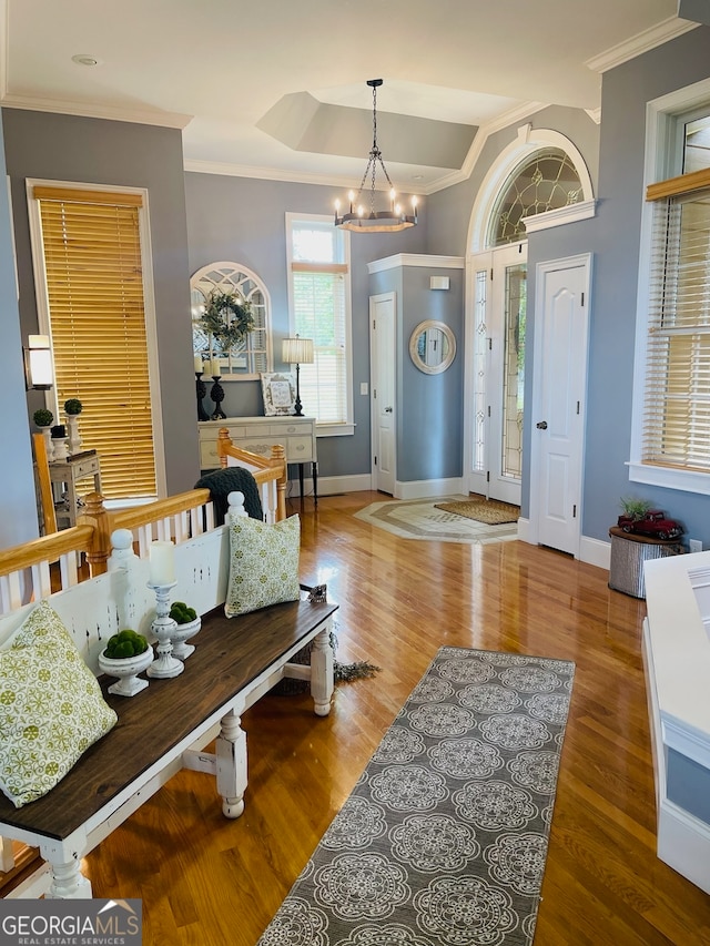 foyer featuring a notable chandelier, hardwood / wood-style flooring, ornamental molding, and lofted ceiling