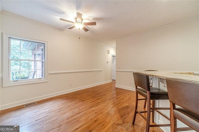 unfurnished dining area with hardwood / wood-style floors, ceiling fan, ornamental molding, and a textured ceiling