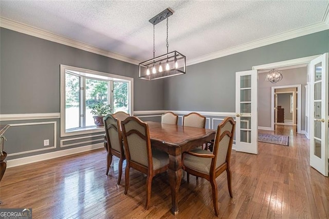 dining area with french doors, ornamental molding, a textured ceiling, a notable chandelier, and hardwood / wood-style floors