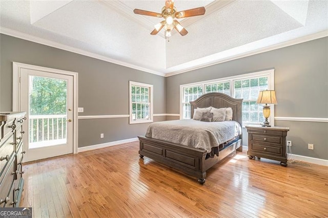 bedroom featuring access to exterior, light hardwood / wood-style floors, a raised ceiling, and ceiling fan