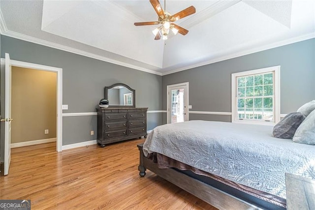 bedroom with ceiling fan, a raised ceiling, crown molding, and light hardwood / wood-style flooring