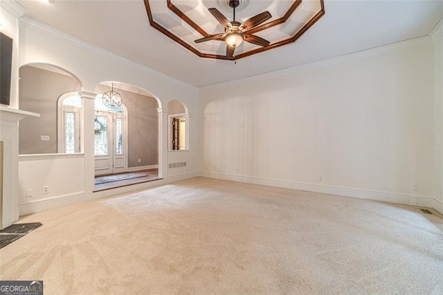 empty room with a tray ceiling, ceiling fan, light colored carpet, and ornamental molding