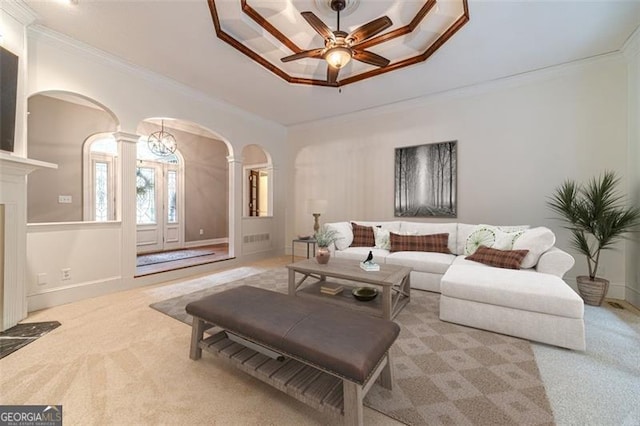 carpeted living room with ceiling fan, crown molding, and a tray ceiling