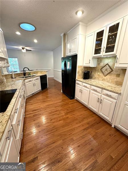 kitchen with black appliances, white cabinets, and hardwood / wood-style flooring