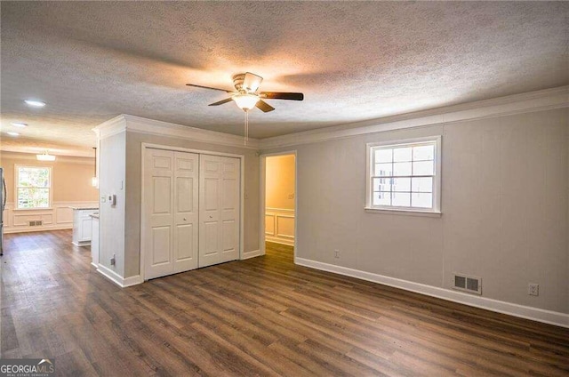 unfurnished bedroom with dark wood-type flooring, ceiling fan, crown molding, and a textured ceiling