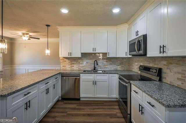 kitchen featuring appliances with stainless steel finishes, white cabinetry, sink, and pendant lighting