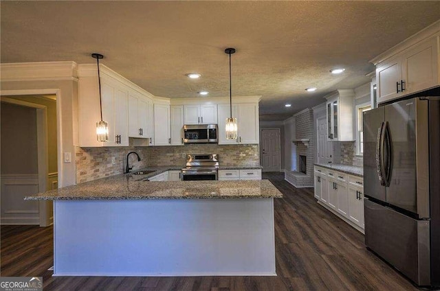 kitchen featuring dark wood-type flooring, white cabinets, stainless steel appliances, and hanging light fixtures