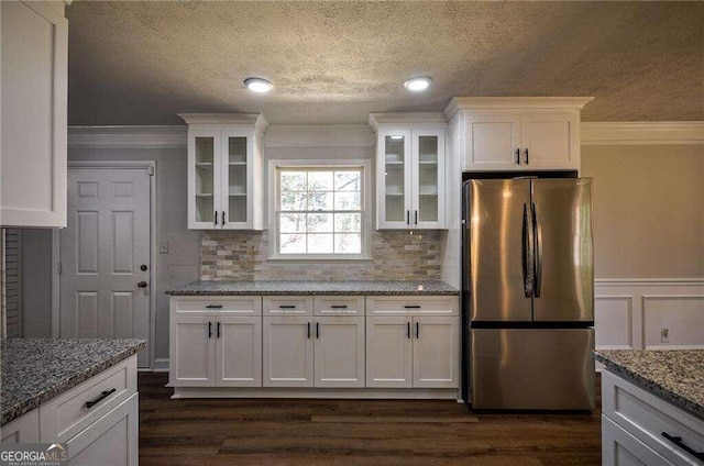 kitchen featuring dark wood-type flooring, ornamental molding, light stone countertops, white cabinetry, and stainless steel refrigerator