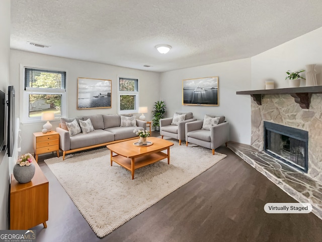 living room featuring a stone fireplace, a textured ceiling, and a wealth of natural light