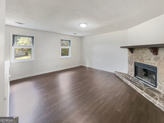 unfurnished living room featuring a textured ceiling, dark hardwood / wood-style floors, and a wealth of natural light