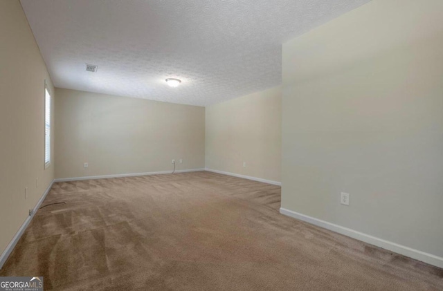 carpeted empty room with a textured ceiling