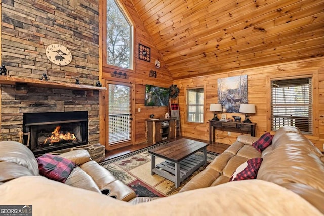 living room featuring a stone fireplace, a wealth of natural light, hardwood / wood-style floors, wooden walls, and wooden ceiling