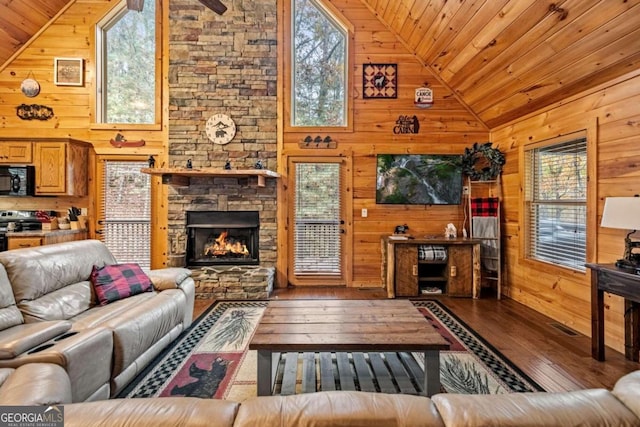 living room with a stone fireplace, a healthy amount of sunlight, wooden ceiling, and wood walls