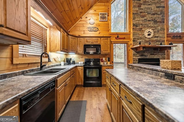 kitchen with a stone fireplace, sink, wooden ceiling, light hardwood / wood-style floors, and black appliances