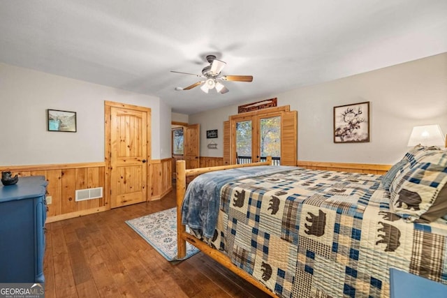 bedroom with ceiling fan, wooden walls, dark hardwood / wood-style flooring, and french doors