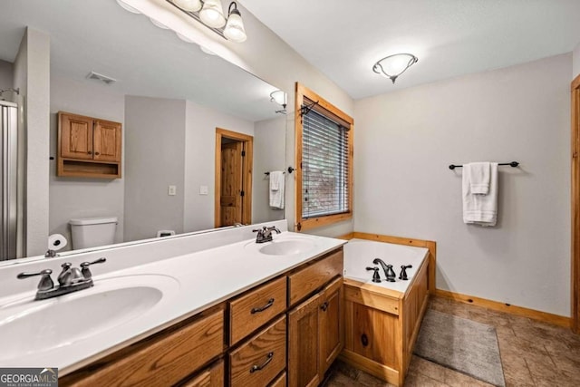 bathroom featuring vanity, a tub to relax in, and toilet